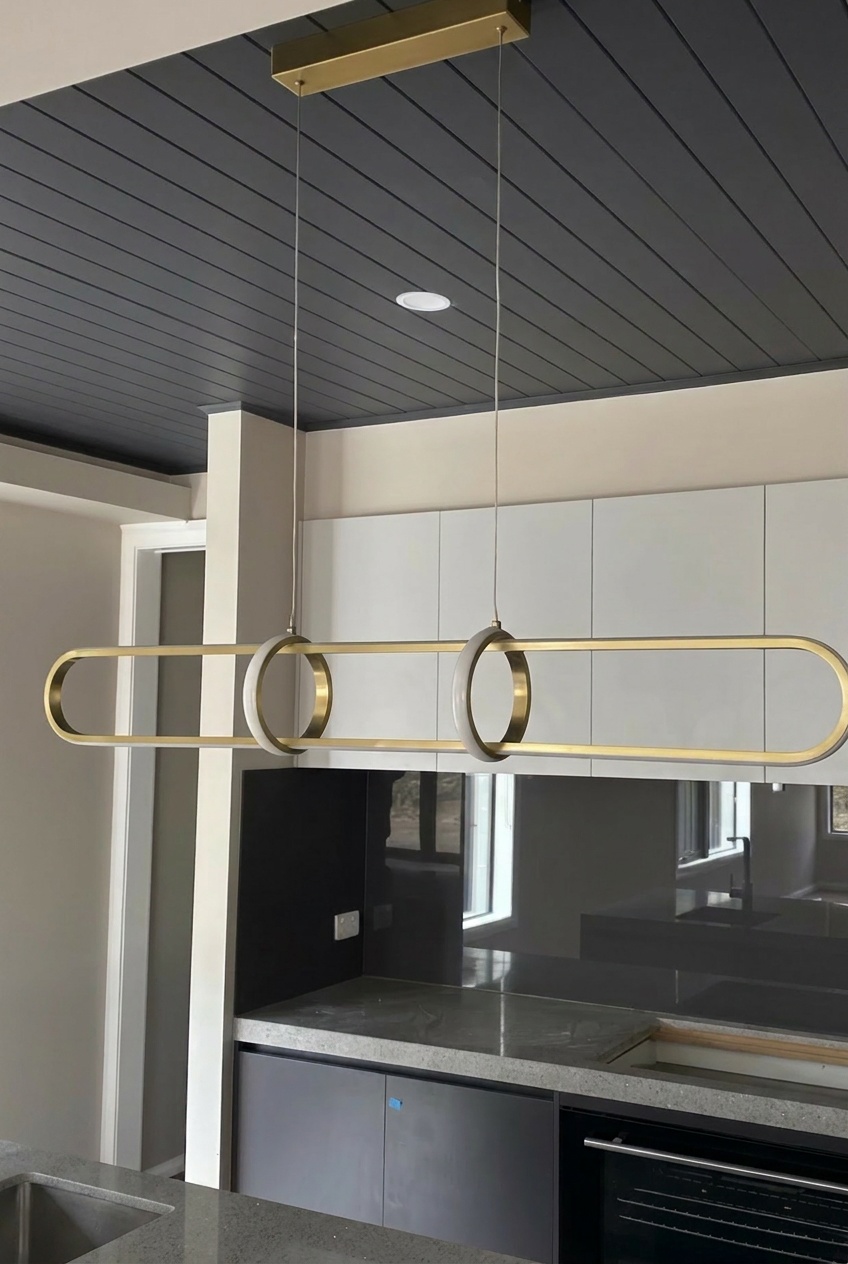 Gold ring linear pendant over kitchen island
